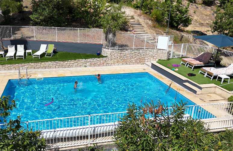 Piscine rectangle bleu entourée par la nature cévenole. Deux enfants jouent dedans.